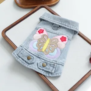 Pet denim jacket detail showing the colorful butterfly embroidery patch and metal leash D-ring.