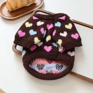 Primer plano de un suéter de punto para mascotas marrón con patrones de corazones coloridos.