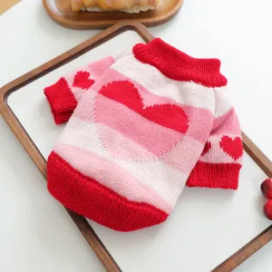 Primer plano del jersey de punto para mascotas a rayas rosa y rojas con detalle de corazones.