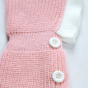 Detailed view of cute pet knit hat with ruffed edge and white buttons, soft texture.