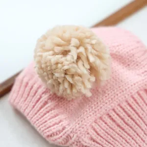 Gros plan détail du bonnet tricoté rose pour animaux avec pompon beige pour chats