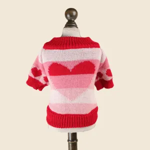 Primer plano detallado del suéter tejido para mascotas, rayas rosas y rojas con diseño de corazón.
