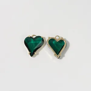 Nahaufnahmedetail grüner facettierter Herzanhänger mit goldenem Metallrahmen für Schmuck.