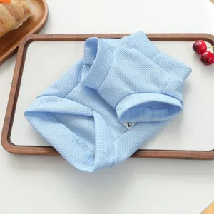 Vue détaillée d'une chemise pour animal en tissu gaufré bleu doux sur un plateau en bois.