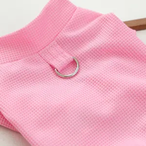 Gros plan détail de vêtements pour animaux en tricot gaufré rose avec anneau en métal.
