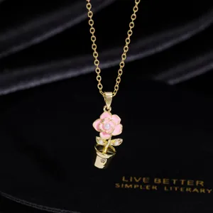 Nahaufnahme einer zarten goldfarbenen Halskette mit einem charmanten rosa Topfblumen-Anhänger.