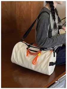 Large capacity white cylindrical gym duffel bag with stylish orange braided handles for travel.