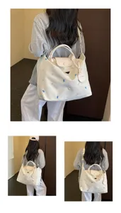 Canvas tote travel bag detail showing embroidered bows, leather flap, and shoulder strap design.