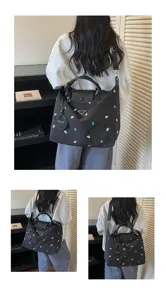 Detail view of the black nylon travel shoulder bag with embroidered bow patterns and straps.