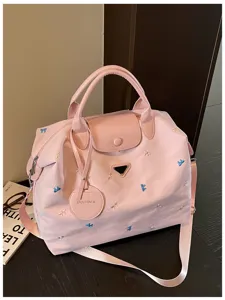 Pink travel duffel bag detail showcasing embroidered bows, sturdy handles, and front badge.