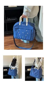 Vista dettagliata della grande borsa da viaggio blu dotata di un grazioso ricamo con fiocco.