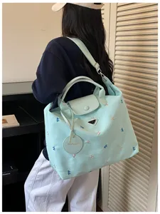 Detailed view of light green travel bag, delicate embroidery, sturdy handles, stylish choice.