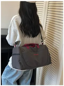 Large capacity travel bag detail showing durable grey fabric and wine-red handles.