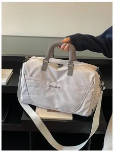 Detail shot of a casual light grey travel duffel bag featuring top handles and a shoulder strap.