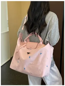 Large capacity nylon travel bag with cute bow embroidery, durable handles and top flap closure.