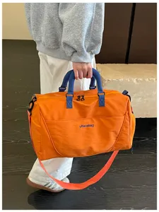 Large capacity travel duffel bag with blue handles and orange shoulder strap for gym and sports.
