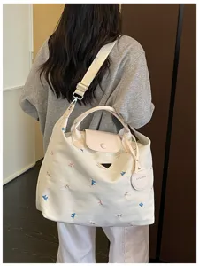 Detailed shot of large capacity canvas travel handbag with cute embroidery and shoulder strap.