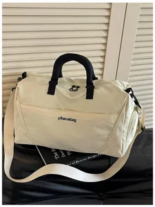 Detail view of off-white travel duffel bag with black handles, gym and weekend bag.