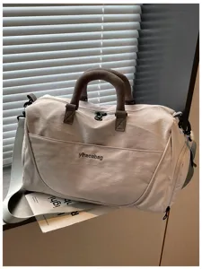 Durable beige travel duffel bag detail showcasing sturdy brown handles and adjustable strap.