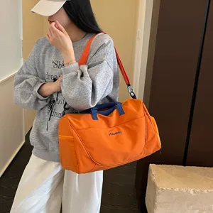 Large capacity travel duffel bag with shoulder strap, stylish orange gym bag for sports.