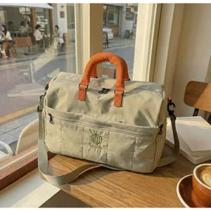 Detailed view of the casual beige travel duffel bag featuring stylish orange handles and pocket.