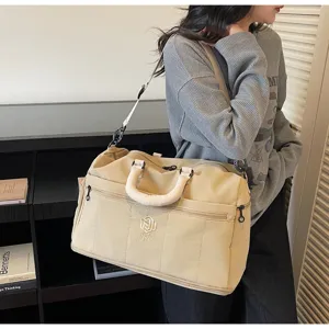 Detailed view of casual beige travel duffel bag with shoulder strap and front zipper pocket.