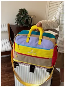 Detailansicht der farbblockierten Reisetasche mit stabilen Griffen und vorderen Fächern.
