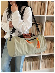 Large capacity cylindrical gym duffel bag with stylish orange woven handles and shoulder strap.