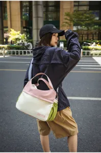 Detailed view of the color-blocked travel shoulder bag, showing pink, white, and green panels.