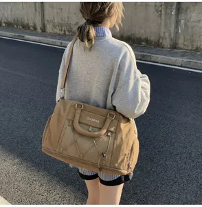 Close-up view of a large khaki travel duffel bag with mesh pocket worn outdoors.