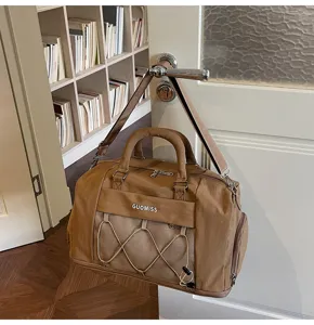 Detailed view of the brown travel duffel bag hanging on a door, showing the mesh pocket.