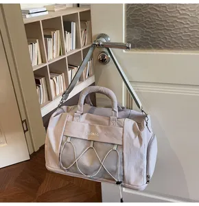 Detailed view of the light grey large capacity travel fitness bag hanging on door.