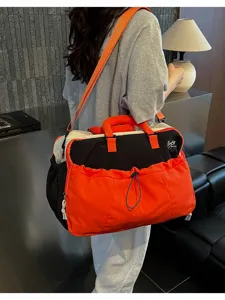 Detailansicht der großen Reisetasche mit stilvollem orange-schwarzem Farbblock-Design.
