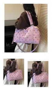 Detail view of the pink corduroy travel duffel bag with cute strawberry pattern and shoulder strap.