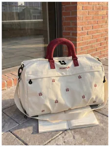 Canvas travel bag with red handles and cute embroidery, spacious for weekend trips.