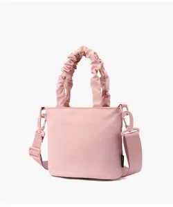 Gros plan détail du sac seau bandoulière en toile rose avec poignée froncée.
