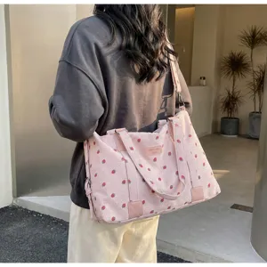 Pink corduroy travel bag detail showing cute strawberry print and sturdy handle design.