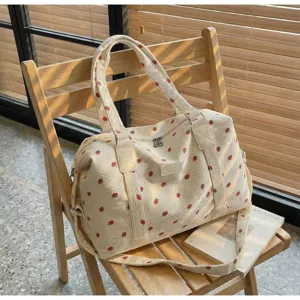 Detail view of a corduroy travel duffel bag with cute strawberry print and sturdy shoulder strap.