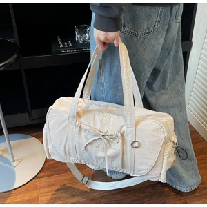 Close-up detail of the large capacity beige travel duffel bag showing front pocket and strap hardware.