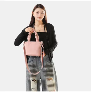 Vue détaillée d'un sac seau en toile rose tendance avec poignées froncées et sangle.