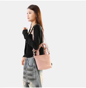 Vue détaillée du sac seau rose à poignée plissée, mettant en valeur la texture et la sangle.