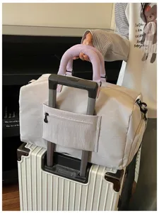 Travel duffel bag detail, light grey luggage bag with purple handle, sleeve for suitcase.