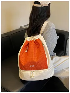 Vue détaillée d'un sac à dos élégant à cordon avec motif à carreaux orange et compartiment étanche.