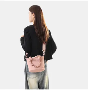 Vue détaillée d'un sac seau en toile rose élégant avec poignée à volants portée.