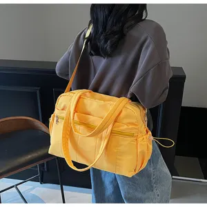 Detailansicht der gelben Reisetasche über der Schulter, zeigt Tragegurte und großes Volumen.