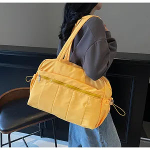 Nahaufnahme zeigt die geräumige gelbe Reisetasche mit Reißverschlusstaschen und Gurten.