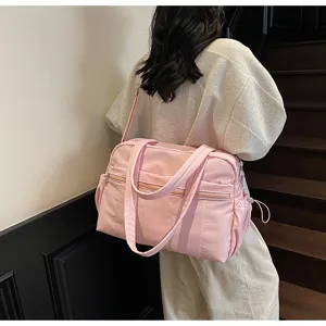 Nahaufnahme der rosa Reise-Duffeltasche am Modell, die das praktische Seitentaschen-Design zeigt.