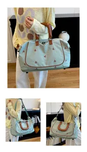 Detailed view of the canvas travel duffel bag showing bow embroidery and leather handle.
