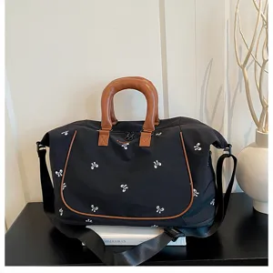 Black travel duffel bag with brown leather handles and cute white bow embroidery for women.