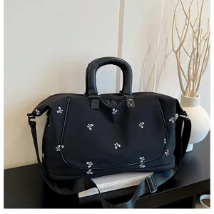 Detail shot of black travel gym bag with white bow pattern, featuring sturdy handles and strap.